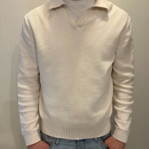 vit tröja med krage - Säljer en stilren vit stickad tröja med klassisk krage och v-ringad hals. Tröjan har lång ärm och ribbade muddar vid ärmslut och nederkant. Perfekt för en clean och enkel look.