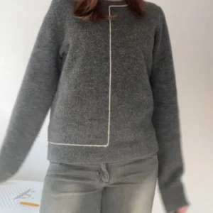 Mörkgrå stickad tröja med vit kant - Mysig mörkgrå stickad tröja med en vit linje. Tröjan är i storleken XL men passar som S🥰