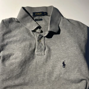 Polo Ralph Lauren piké - Säljer en klassisk grå pikétröja från Polo Ralph Lauren i modellen Custom Fit. Storlek XL men passar mer som L/M. Pris 250kr, men kan diskuteras. Hör av er om ni har frågor :)