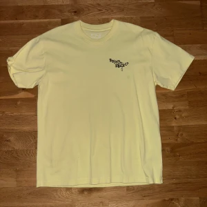 Ljusgul t-shirt från Polar Skate Co - Ljusgul t-shirt från Polar Skate Co i bomull. Liten logga tryckt på bröstet och stor grafisk illustration på ryggen. Klassisk passform och rund halsringning. Perfekt för dig som gillar unika prints
