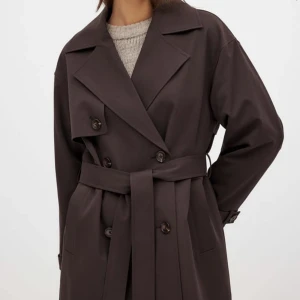 Mörkbrun trenchcoat med bälte - Intressekoll för den här supersnygga trenchcoaten från nakd. Stilren mörkbrun trenchcoat med klassisk krage, dubbelknäppning och knytskärp i midjan. Säljs i nyskick, använd två gånger 🫶🏼 inköpt för 1 000 kr och är slutsåld på hemsidan