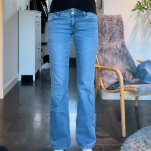 Ljusblå bootcut jeans - Säljer ett par ljusblå jeans med bootcut passform och klassisk femficksdesign. Jeansen har normalhög midja och stängs med dragkedja och knapp. Perfekta för en avslappnad och trendig look.