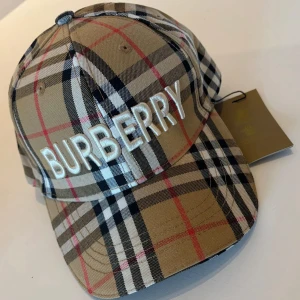 Rutig keps från Burberry - Säljer en klassisk rutig keps från Burberry i beige, svart, vit och röd. Kepsen har tydlig broderad logga framtill och justerbar passform. Perfekt accessoar för en trendig look. Möts (Malmö) och fraktas. För mer kepsar kom privat 