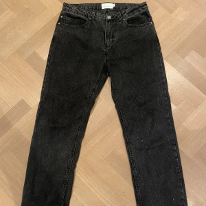 Svarta raka jeans - Svarta jeans med rak passform och klassisk femficksdesign. Jeansen har normalhög midja och stängs med dragkedja och knapp. Perfekta till vardags för en avslappnad stil. I storlek 34/32