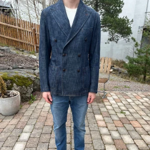 Tagliatore - Dubbelknäppt denimkavaj - Säljer en exklusiv dubbelknäppt denimkavaj från det italienska lyxmärket Tagliatore, känt för sina skräddade silhuetter, kvalitetsmaterial och tidlös stil.  Kavajen är i storlek 50R och har en snygg, modern passform som kombinerar det klassiska med en lite mer avslappnad känsla tack vare det mjuka denimtyget. Perfekt för dig som vill ha ett alternativ till den vanliga kavajen – lika snygg till chinos som till jeans.  Den är i mycket fint skick, sparsamt använd och välvårdad. 