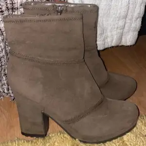Säljer ett par bruna boots i mocka med hög klack och rund tå. Skorna har dragkedja på sidan för enkel påtagning och en stilren design som passar till många outfits. Sparsamt använda, fina!