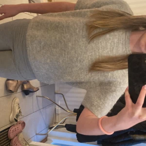 Grå stickad kortärmad tröja från Gina Tricot - Mysig grå stickad tröja från Gina Tricot med korta ärmar och rund halsringning. Tröjan har en mjuk och fluffig känsla, perfekt för lager-på-lager eller som den är. Enkel och stilren design som passar till mycket.