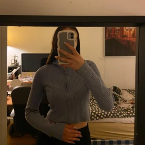 Blå ribbad croppad tröja från Monki - Säljer en blå ribbad tröja från Monki i croppad modell. Tröjan har dragkedja framtill och lång ärm. Perfekt för dig som gillar en tight och stilren look. Fråga gärna om du undrar något!