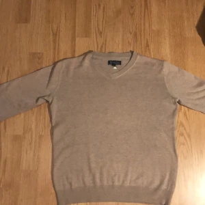 Beige v-ringad tröja från Massimo Dutti - Klassisk beige v-ringad tröja från Massimo Dutti. Tröjan har lång ärm och ribbade muddar vid ärmslut och nederkant. Perfekt för en stilren och enkel look. Priset är inte hugget i sten 