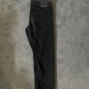 Svarta jeans från Jack & Jones - Säljer ett par svarta jeans från Jack & Jones med klassisk femficksdesign och rak passform. Jeansen har en snygg svart tvätt och är tillverkade i ett mjukt bomullsmaterial. Storlek W32 L32.