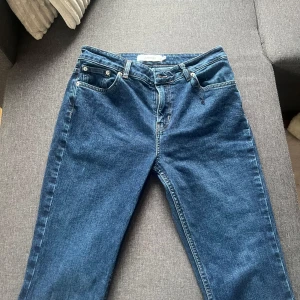 Blå jeans från Junkyard - Säljer ett par klassiska blå jeans från Junkyard i modell med normal passform. Jeansen har fem fickor, knappgylf och raka ben. Perfekta till vardags och lätta att matcha med olika stilar.