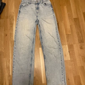 Ljusblå raka jeans - Säljer ett par ljusblå jeans med rak passform och hög midja. Klassisk femficksmodell med dragkedja och knapp framtill. Perfekta till vardags för en avslappnad stil. Innebenslängd 72 cm