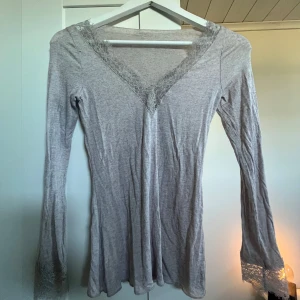 Ljusgrå långärmad topp med spets från intimissimi  - Säljer en ljusgrå långärmad topp från intimissimi. Toppen har v-ringning och fina spetsdetaljer både vid halsringningen och vid ärmsluten. Perfekt för dig som gillar en enkel men ändå detaljrik stil. Jätte skön men ett litet lagat hål längre ner på ryggen. Inget jag har märkt sen jag köpte den här på plick därför syns det knappt!💞