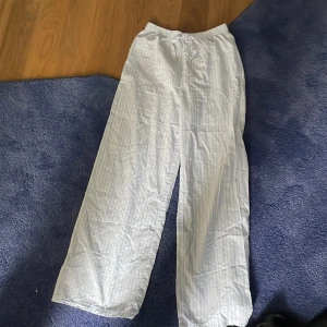 Vita randiga pyjamasbyxor/byxor från H&M - Lätta och luftiga vita byxor med tunna vertikala ränder från H&M. Byxorna har resår i midjan och raka, vida ben. Perfekta för varma dagar eller som mysbyxor hemma.