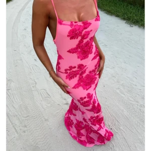 Rosa långklänning från Ivy&Rose - Supersnygg rosa långklänning från Ivy Rose med tunna axelband och stora blommiga applikationer i mörkare rosa. Klänningen har figurnära passform och är perfekt för sommarens alla tillfällen. Materialet känns mjukt och följsamt. Aldrig använd då den inte passade mig, prislapp är kvar. 