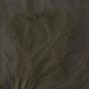 Vit spetsblus med stjärnmönster från Bershka - Säljer en genomskinlig vit spetsblus från Bershka med korta ärmar och stjärnmönster över hela tyget. 