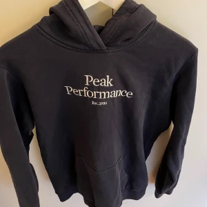 Mörkblå hoodie från Peak Performance - Säljer en mörkblå hoodie från Peak Performance då den inte kommer till användning längre. Passar XS/S