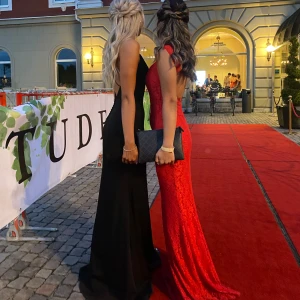 Balklänning  - Säljer en elegant röd långklänning med spetsdetaljer och figurnära passform. Klänningen har vackert öppen rygg och breda axelband. Perfekt för bal eller fest. Klänningen är i ett spetsliknande material och har en klassisk, feminin siluett. Använd 1 gång på min bal. Jag är 160 och klänningen var gick ner till marken med klackar. 