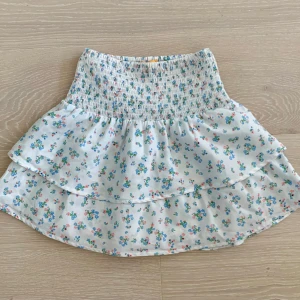Vit blommig kjol från Gina Tricot - Supersöt, kort och stretchig kjol från Gina tricot i storlek 146/152 som också passar xxs-xs. Den är mycket bra skick och har inga defekter.