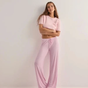 Ljusrosa mjukisbyxor från Nelly - Säljer ett par så fina ljusrosa mjukisbyxor från Nelly med dragsko i midjan. Byxorna har en loose passform och är tillverkade i ett mjukt, ribbat material som är perfekt för en avslappnad stil. Jättefina och sköna, helt nya och oanvända!! Säljer pga hade 2!