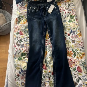 Mörkblå bootcut jeans från Miss Me - Säljer ett par mörkblå midwaist boutcut jeans från Miss Me med snygga broderade bakfickor. Aldrig använda!! Byxorna är storlek 27 men passar dig som har 28 och möjligtvis 29. Väldigt populära som många söker efter och perfekt för dig som gillar att hoppa på trender!