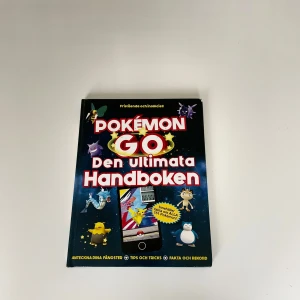 Pokémon GO Den ultimata Handboken - En färgglad och informativ bok om Pokémon GO, fylld med tips, tricks, fakta och rekord. Omslaget är svart med stora röda och vita bokstäver samt bilder på olika Pokémon. Perfekt för dig som vill bli bättre på spelet och anteckna dina fångster.