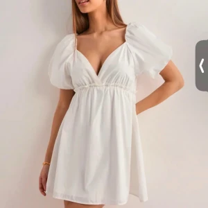 Vit kortklänning med puffärmar från Nelly - Supersöt vit kortklänning från Nelly med djup v-ringning och puffiga kortärmar. Har endast testat den, så i nyskick! 😊