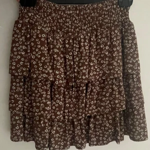 Brun blommig volangkjol - Söt brun kjol med små vita blommor och flera volanger. Resår i midjan så skulle säga att den passar xs-s💞