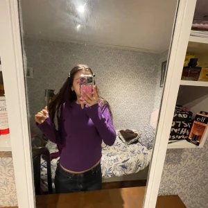 Lila långärmad bomullströja - Säljer en enkel och stilren lila långärmad tröja i 100% bomull. Tröjan har en rund halsringning med liten v-formad detalj framtill. Perfekt för dig som gillar färg och vill ha något bekvämt till vardags.