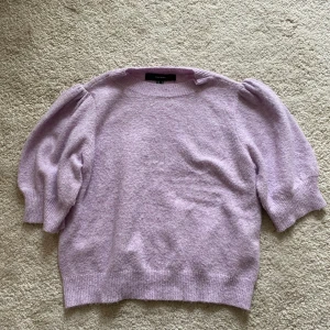 Ljuslila stickad tröja från Vero Moda - Superfin ljuslila stickad tröja från Vero Moda med puffärmar och rund halsringning. Tröjan har en mjuk och mysig känsla, ribbade muddar och en något lös passform. 