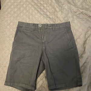 Mörkgrå shorts från Celio - Snygga mörkgrå shorts från Celio med klassisk design. Shortsen har två sidofickor, två bakfickor med knapp och stängs med dragkedja och knapp framtill. Perfekta för varma dagar och enkel att matcha med olika outfits. Kontakta för mer bilder🌟
