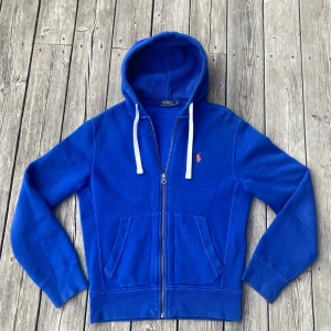 Blå hoodie från Polo Ralph Lauren - Blå Ralph Lauren hoodie i mycket bra skick! Bara använd enstaka gånger, Tröjan är i storlek S och personen på bilden är 176 cm och väger 60 kg. Hör av er om frågor!