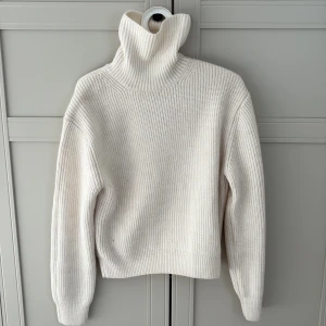 Vit stickad polotröja från H&M - Säljer en stilren vit stickad polotröja från H&M. Tröjan har en hög polokrage och långa ärmar, perfekt för kyligare dagar. Den är mjuk och bekväm, idealisk för både vardag och mysiga stunder hemma. Passa på att fynda denna klassiska tröja! Pris kan diskuteras 