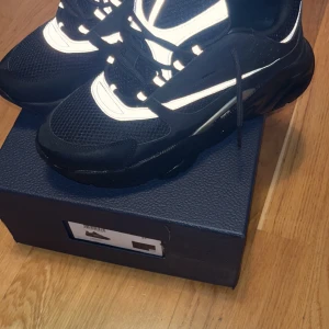 Svarta sneakers från Dior - Snygga svarta sneakers från Dior med reflekterande detaljer och snörning. Perfekta för en stilren look med en modern touch. Använda 3 gånger bara! Pris kan diskuteras och fraktar samma dag