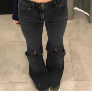 Svarta bootcut jeans med slitningar - Snygga svarta bootcut jeans med håliga knän (klippta själv) säljer pgr av att dom inte kommer till användning skriv för fler bilder osv (lånad bild) köp via plick ❤️