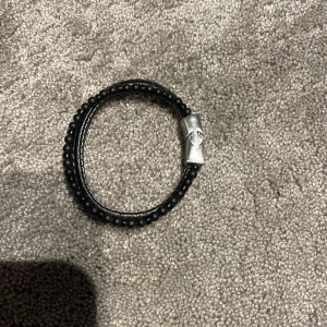 Svart armband med silverdetalj - Snyggt svart armband med små pärlor och en stilren silverfärgad låsdetalj. Perfekt accessoar för att ge din stil en extra touch. Köpt på ur och Penn för 400kr 