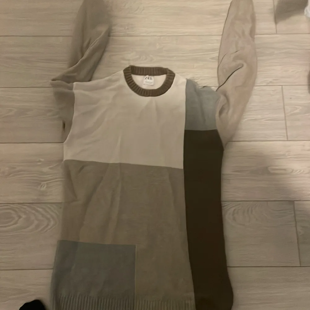 Säljer en snygg stickad tröja från Zara i olika nyanser av beige och brun. Tröjan har ett blockmönster och långa ärmar, perfekt för kyligare dagar. Den är tillverkad i Turkiet och har en bekväm passform.. Neuletakit & Villapaidat.