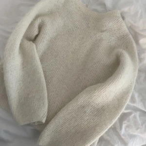 Vit stickad tröja - Mysig vit stickad tröja med långärmad design. Perfekt för kyligare dagar med sin mjuka och bekväma passform. En klassisk och stilren tröja som passar till det mesta.