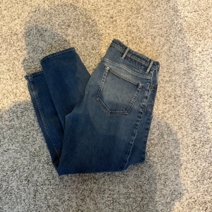 Blå jeans från Acne studios - Snygga blå jeans från Acne studios Blå Konst med klassisk femficksdesign och knappgylf. Storlek 34/32 Mycket bra skick förutom att bakre patchen är lite skadad( syns på bild 5). Perfekta för en avslappnad stil. De har en rak passform och är tillverkade i ett slitstarkt denimtyg.