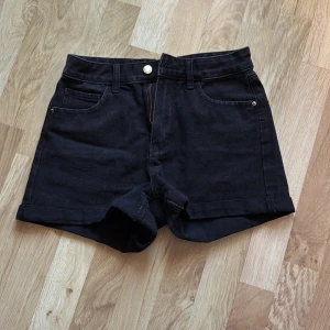Svarta jeansshorts från Shein - Snygga svarta jeansshorts från Shein med klassisk femficksdesign och knappgylf. Perfekta för en avslappnad stil. De har en högmidjad passform som ger en smickrande siluett. Passar perfekt till sommarens alla äventyr!