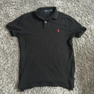 Raffe piké tröja  -  Öppen för byten🙌.                                             Svart pikétröja från Ralph Lauren i modellen Custom Slim Fit. Klassisk krage, korta ärmar och två knappar framtill. Tillverkad i mjuk bomull, perfekt för en clean och stilren look. Pris kan diskuteras👀🙌