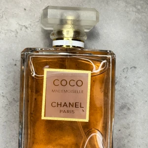 Chanel Coco Mademoiselle EdP 100ml - Chanel Coco Mademoiselle Eau de Parfum i 100ml flaska. Klassisk rektangulär glasflaska med guldig-orange vätska och frostad fyrkantig kork. Elegant etikett med guldiga detaljer och tydlig Chanel Paris-logga. Perfekt för dig som gillar lyxiga och ikoniska dofter.
