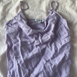 Ljuslila linnetopp - Supersöt ljuslila linnetopp som har tunna axelband och en snygg draperad urringning framtill. Materialet känns mjukt och lätt mot huden. Den är lite skrynklig men säg till om du vill att jag ska stryka innan du köper den. Köpt från Kappahl och kommer inte mer till användning. Kontakta gärna innan köp!