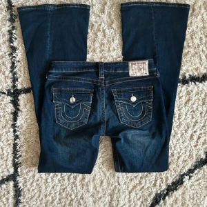 Mörkblå bootcut jeans från True Religion - Säljer ett par mörkblå Trues med bootcut passform. Klassiska kontrastsömmar och femficksmodell. I modellen ”Becca” midrise bootcut. Köpte dessa i förrgår i raglady butiken för 1 299kr och märkte att de är alldeles för långa för mig! Storlek 28