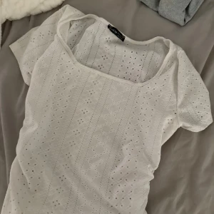 Vit broderad blus från SHEIN - Superfin vit blus från SHEIN med broderade detaljer och hålmönster. Toppen har korta ärmar och en fyrkantig ringning som ger en söt och somrig vibe. Perfekt att matcha med jeans eller kjol för en fräsch look.
