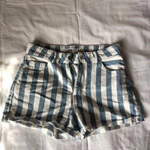 Randiga hög/medelmidjade jeansshorts - Snygga hög/medelmidjade shorts av märket FB Sister (från TJ Maxx i USA) i blåvitt randigt jeansmaterial. Lite misfärgad på ena bakfickan. Storlek M.