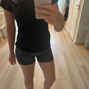 Mörkgrå träningsshorts - Snygga mörkgrå träningsshorts i tight passform. De är highwaist och gjorda i ett stretchigt syntetmaterial som sitter skönt och följer kroppen. Perfekta för gymmet eller löprundan, med diskreta meshdetaljer på sidorna för extra ventilation. Den har även lite scrunch i rumpan för att framhäva lite extra form🏋
