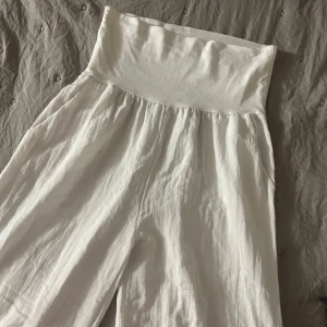 Vita vida linnebyxor  - Säljer ett par superfräscha vita linnebyxor med bred, mjuk. Byxorna har en lös och flowy passform, perfekta för varma dagar. Materialet är svalt och luftigt linne, vilket ger en chill och avslappnad vibe.