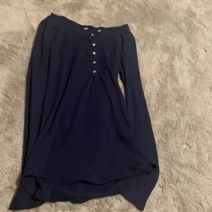 Mörkblå långärmad tröja med knappar - En stilren mörkblå långärmad tröja med dekorativa knappar framtill. Perfekt för dig som gillar enkel och klassisk stil. passar bra till jeans eller kjol. Tyvärr är märket bort klippt med den är i från brandy Melville, står inte storlek men skulle säga att den passar nån som har Xs eller S. Har själv storlek Xs och S och den passar mig.
