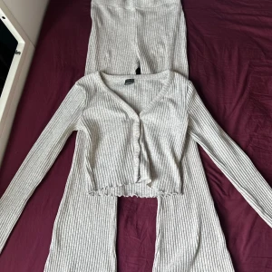 Grå ribbade mjukisbyxor - Säljer ett par grå ribbade mjukisbyxor i mjukt material. Byxorna har en bekväm passform och elastisk midja, perfekta för chill dagar hemma. Snyggt randigt mönster och stretchigt tyg som gör dem extra sköna.